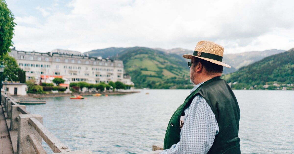 Mann mit Strohhut blickt über den Zeller See zum Grand Hotel Zell am See